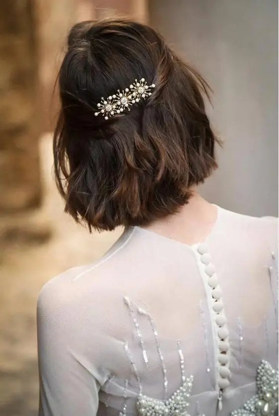a long bob with wavy hair, styled as a half updo, with a beautiful rhinestone hair barrette is wow
