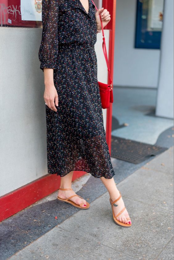 a moody floral midi dress with short sleeves, a red bag and tan Greek sandals
