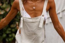 a white lace bralette and a neutral linen romper make up a chic and carefree outfit for a hot day