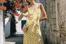 a yellow A-line floral midi dress with straps and a ruffle skirt, a mini bag, slippers and seashell accessories