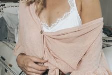 blue ripped denim shorts, a white bralette and a pink oversized cardigan with buttons for a home look