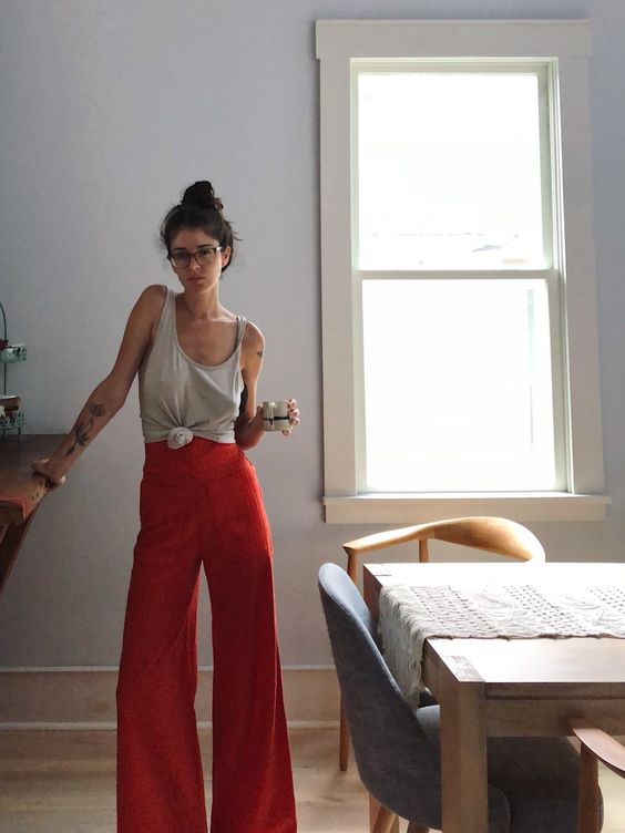 red wide high waisted pants and a grey top on straps is a simple and bright look with a touch of color