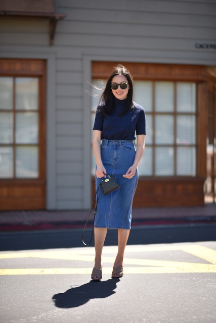 With navy blue turtleneck, black mini bag and gray mules