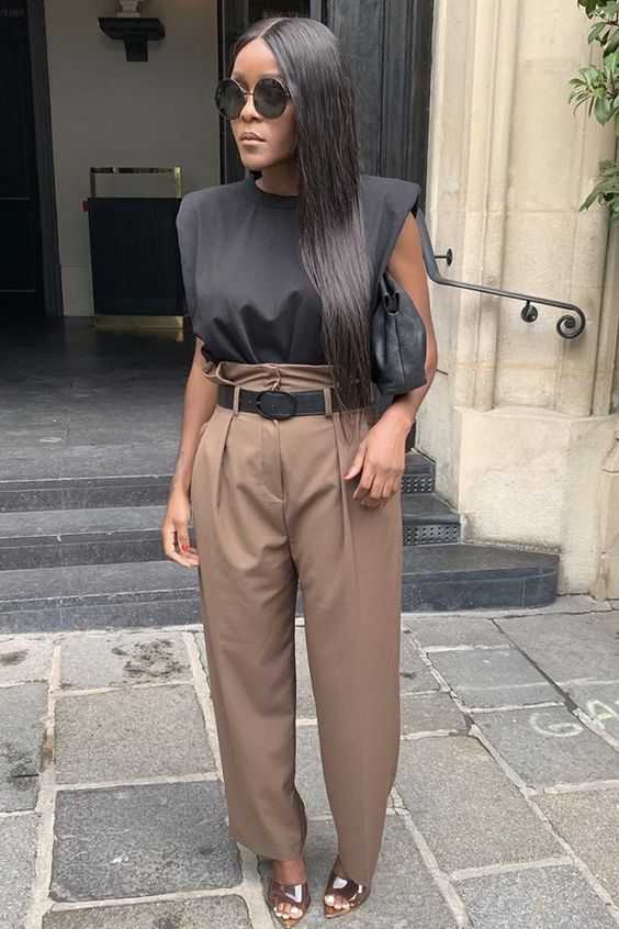 a black padded shoulder top, taupe high waist pants, shiny shoes and a black bag for a statement look
