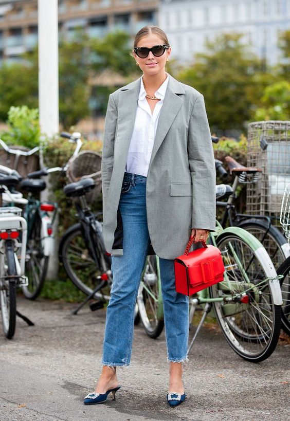 a bold work look with a white button down, a grey oversized blazer, blue jeans, navy embellished mules and a red bag