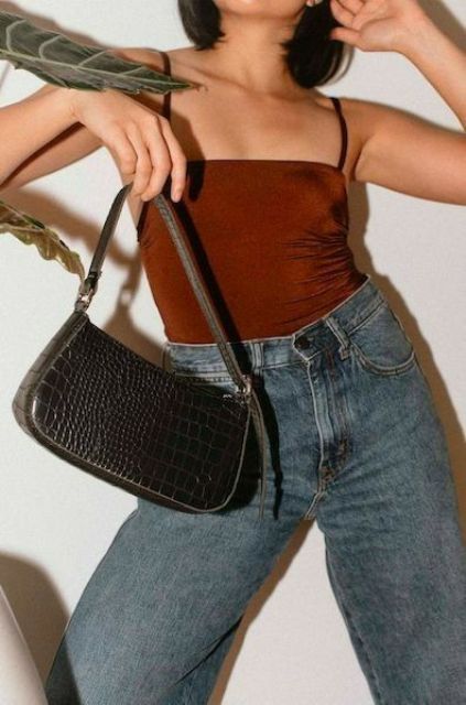 a burgundy spaghetti strap top, blue jeans and a black baguette bag are a cool and simple combo for a party