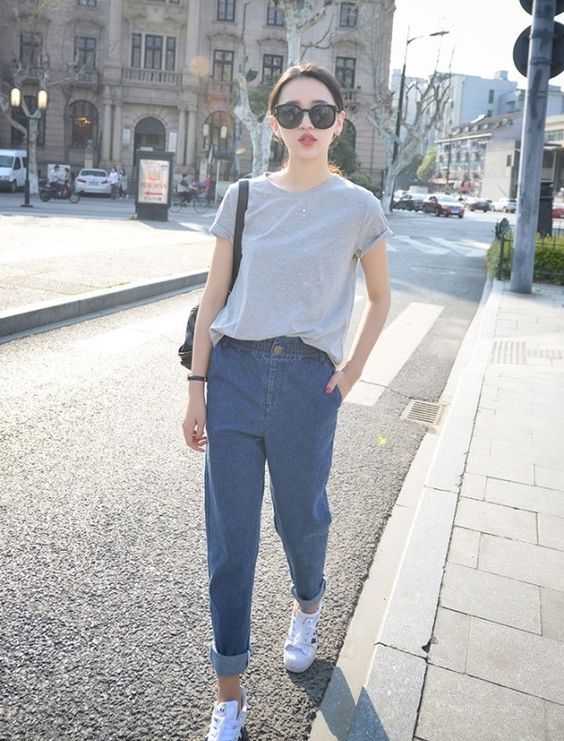 a casual outfit with a grey tee, blue baggy jeans, white sneakers and a black bag