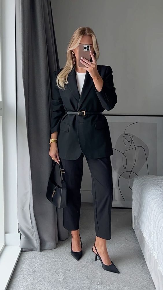 A classy work outfit with a black pantsuit, a white t shirt, a belt, black slingbacks and a baguette bag is chic