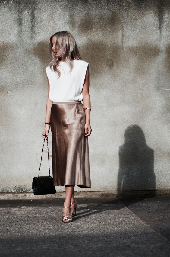 a glam look with a white padded shoulder tee, metallic satin midi skirt, shiny shoes and a black bag