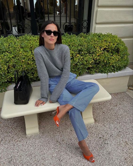 a grey jumper, blue fine stripe pants, orange heeled mules and a black bag for spring or fall
