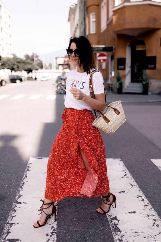 a printed white tee, a red printed midi skirt with a slit, burgundy lace up heels and a wicker bag