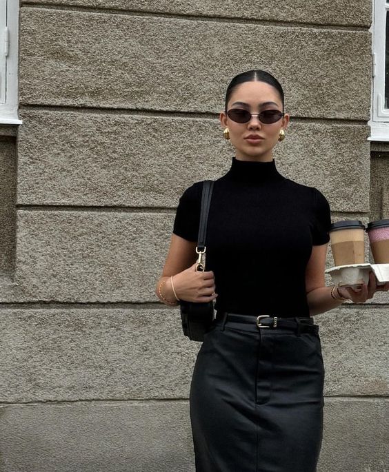 a refined total black look with a short sleeve turtleneck, a leather skirt, a belt and a baguette bag and trendy earrings