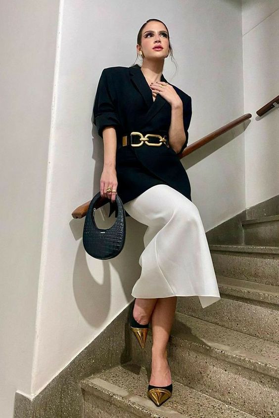 a sophisticated special occasion look with a black blazer, a white midi skirt, black and gold shoes, a gold chain belt and a navy baguette bag