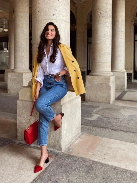 a spring work look with a white button down, blue jeans, a yellow blazer, red heeled mules and a red bag