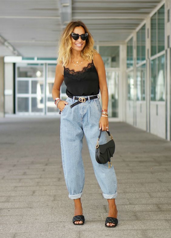 a trendy look with a black lingerie top, blue baggy jeans, black padded mules and a black saddle bag