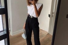 a trendy minimalist look with a white padded shoulder top, black pants, embellished shoes and a small bag