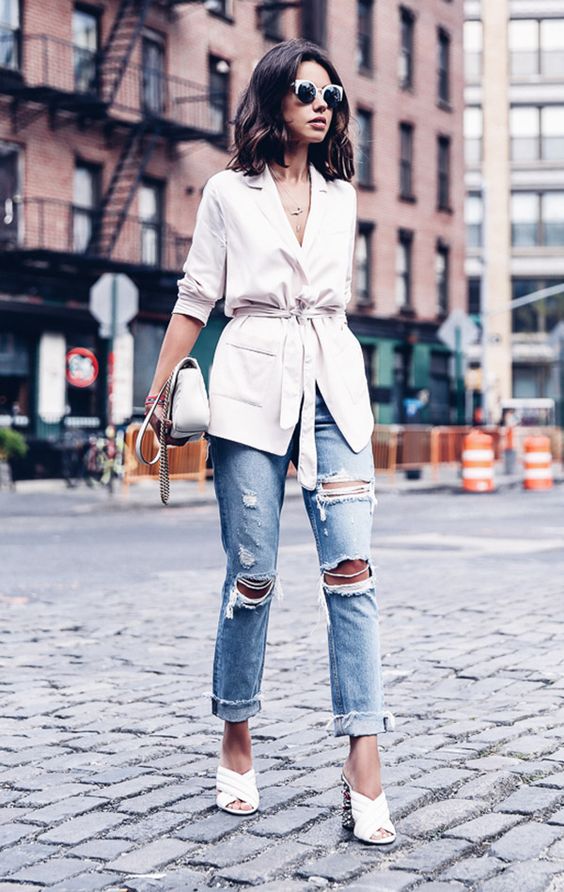 a white blazer, ripped blue jeans, white heeled mules and a white bag for a glam look