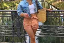 a white crop top, a blue cropped dneim jacket, peachy shorts, white sneakers and a woven bag for summer