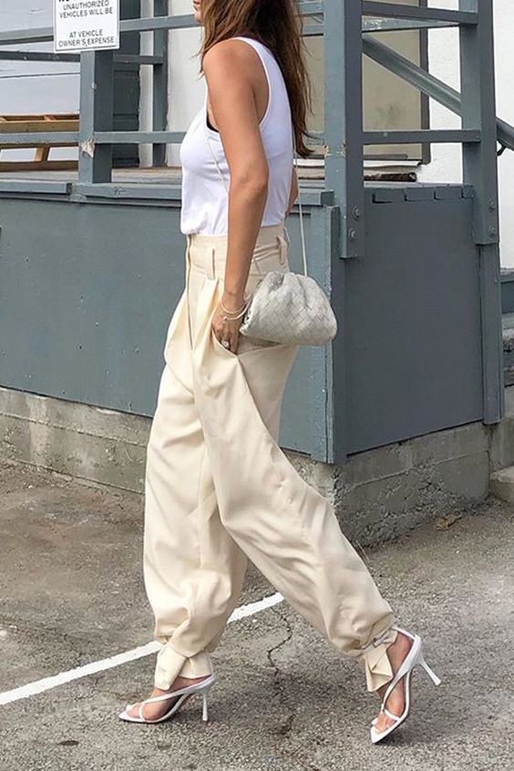 a white sleeveless top, neutral cargo pants with pockets, white square toe sandals, a small woven leather bag