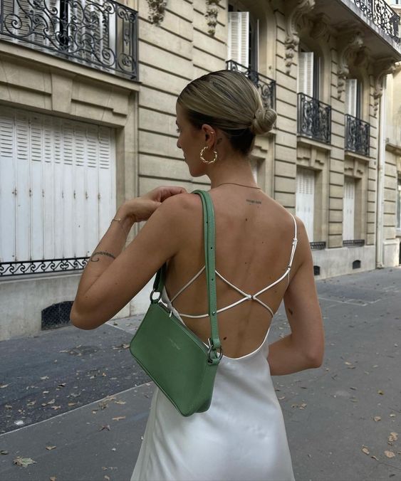 a white slip dress with a criss cross back, statement earrings and a green baguette bag are a lovely combo for a summer look
