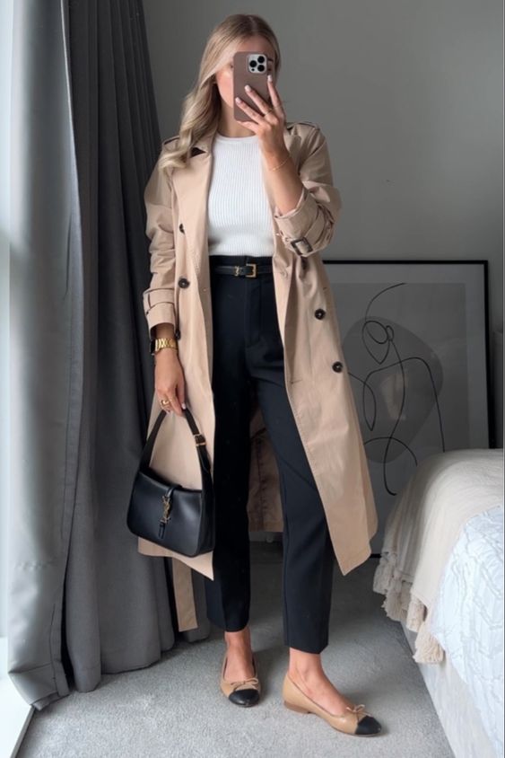 An Old Money spring look with a white top, black trousers, two tone shoes, a beige trench, a black baguette and a black belt