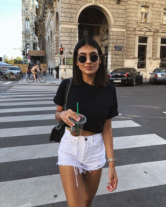 a black crop top, whiet denim ripped shorts and a black crossbody form a monochromatic look