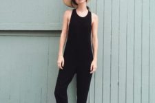 a black plain jumpsuit, white sporty sandals and a hat for a stylish and bold summer look