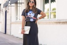 a black printed tee, a black satin midi, white shoes and a white clutch and statement earrings