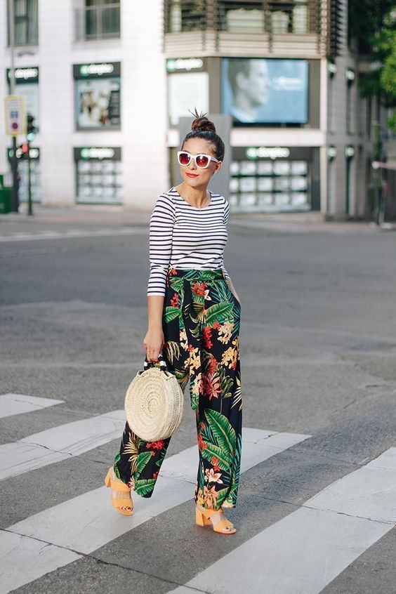 a bright outfit with a striped top, tropical print trousers, yellow block heels and a wicker bag
