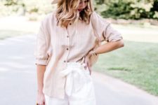 a casual summer look with a tan striped shirt with cuffed sleeves, white paper bag shorts, a neutral bag and a boater hat