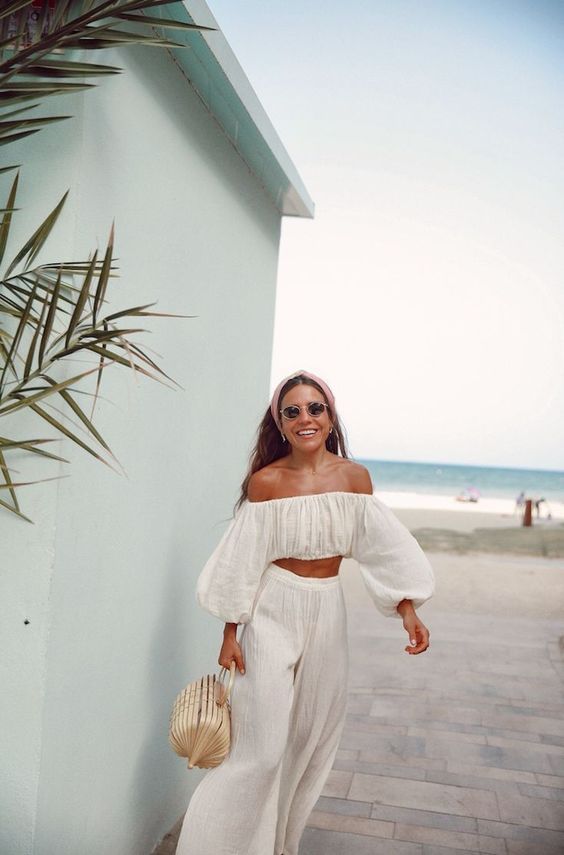 a cool vacation suit with an off the shoulder crop top with long sleeves and wideleg pants plus a wicker bag