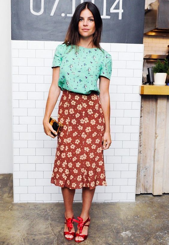 a green floral tee, a burgundy floral midi, red heels and a small clutch for a party