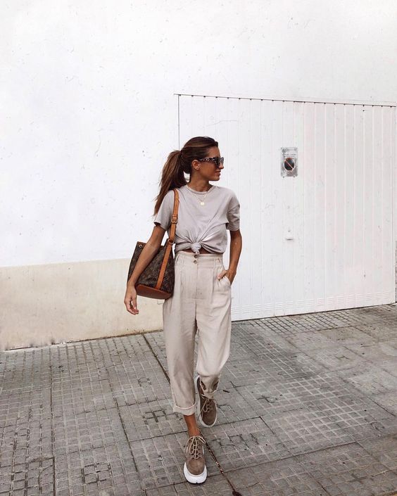 a grey tied up tee, neutral high waisted pants, brown suede trainers and a large tote