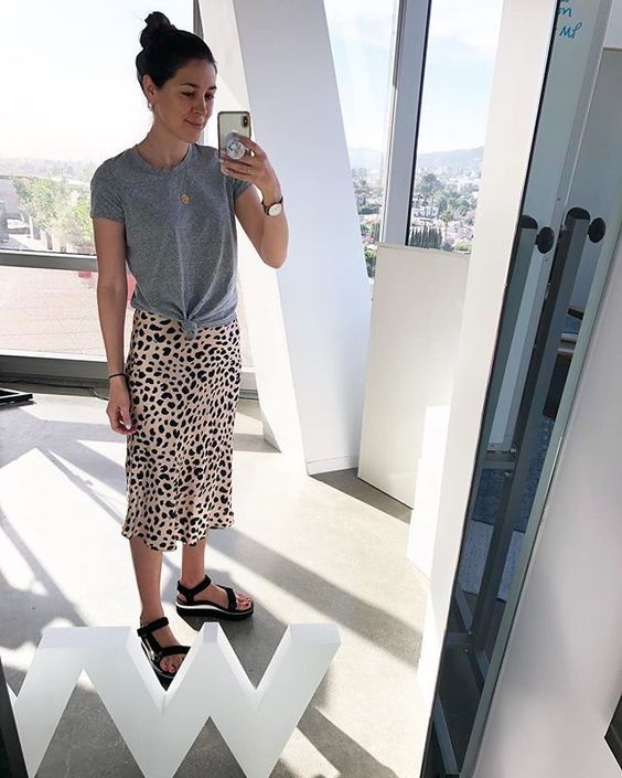 a modern everyday outfit with a grey tied up tee, leopard print midi, blakc sporty sandals and a necklace