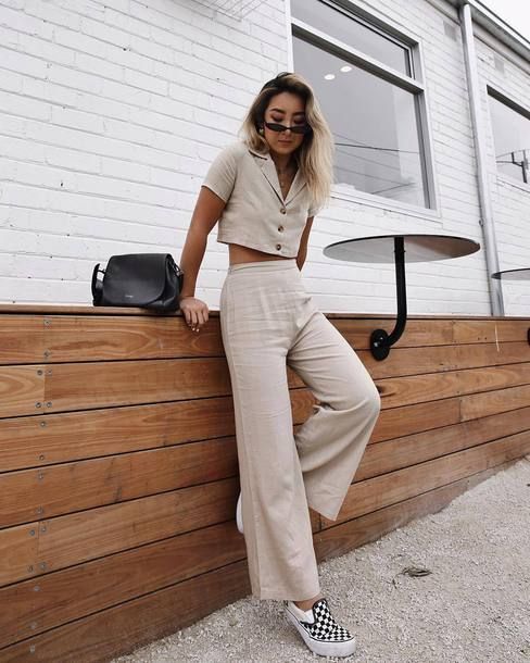 a neutral linen suit with a button up crop top, wideleg pants, checked slipons and a black saddle bag