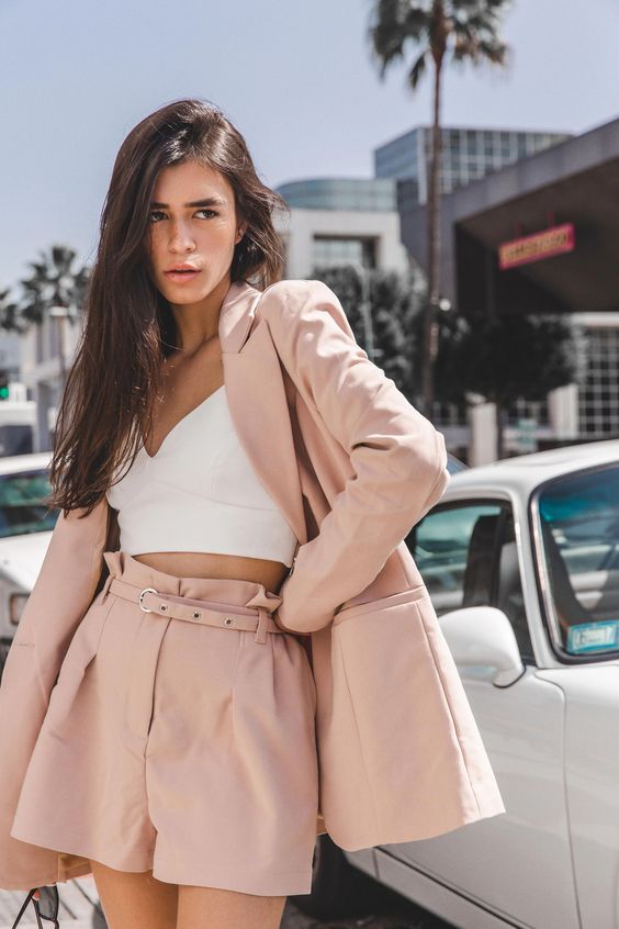 a pink shorts suit with an oversized long blazer and paperbag shorts plus a white bra crop top