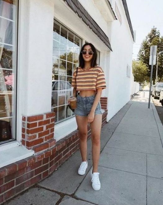 a sporty outfit with a striped crop top, blue denim shorts, white sneakers and a crossbody
