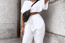 a sporty outfit with a white crop top, joggers, trainers and a black waist bag for summer