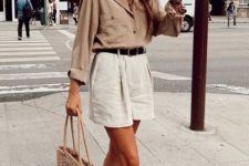 a tan shirt with long sleeves and pockets, white high waisted shorts, woven mules and a wicker bag