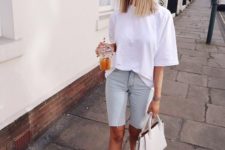a white oversized tee, neutral denim cycling shorts, white sneakers and a white bag