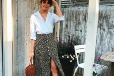 a white shirt, a black floral midi skirt on buttons, brown shoes and a basket bag