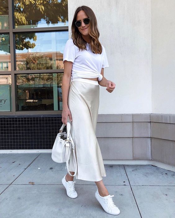 a white tied up tee, a neutral satin midi skirt, white sneakers and a white bucket bag for every day