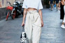 an edgy look with a white crop top, neutral baggy pants, blush heels and an animal print bag