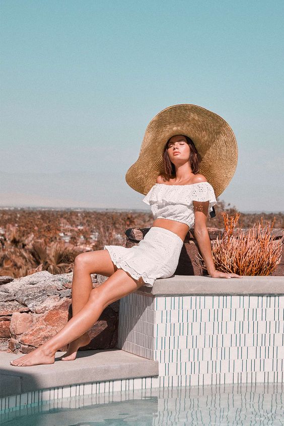 a romantic outfit with a white lace crop top and a mini skirt plus an oversized floppy straw hat