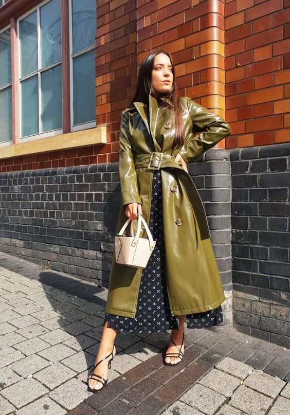 a black printed midi dress, a green leather trench, black strappy shoes and a white bucket bag