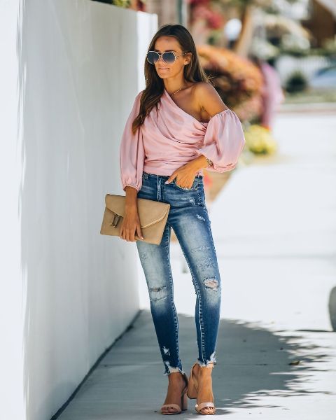 With distressed skinny jeans, beige clutch and beige sandals