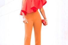 With orange high-waisted trousers and red mini clutch