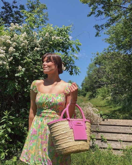 a bright floral summer mini dress with cap sleeves and a square neckline and a hot pink straw bag