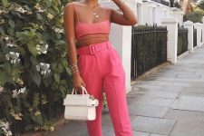 a bright look with a pink bra crop top, high waisted pants, white sneakers and a bag for a hot day