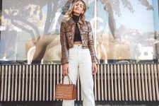 a fall outfit with a black crop turtleneck, white high waisted jeans, white sock booties, a brown snakeskin jacket and an amber top handle bag